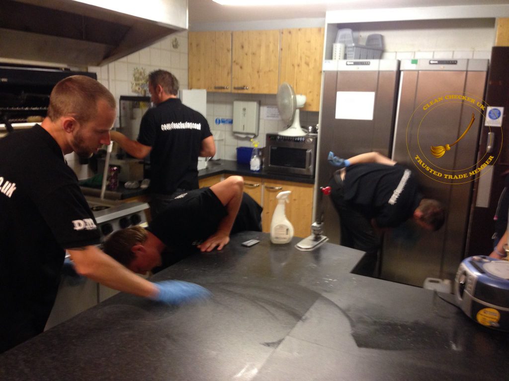 team at Ceep Clear Cleaning working hard cleaning a kitchen and oven.